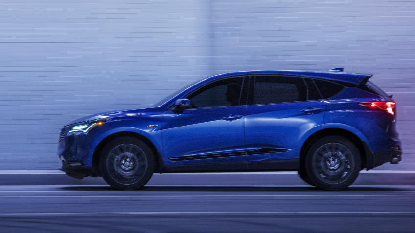 Blue Acura MDX drives through the city. / Acura MDX bleue roulant en ville.